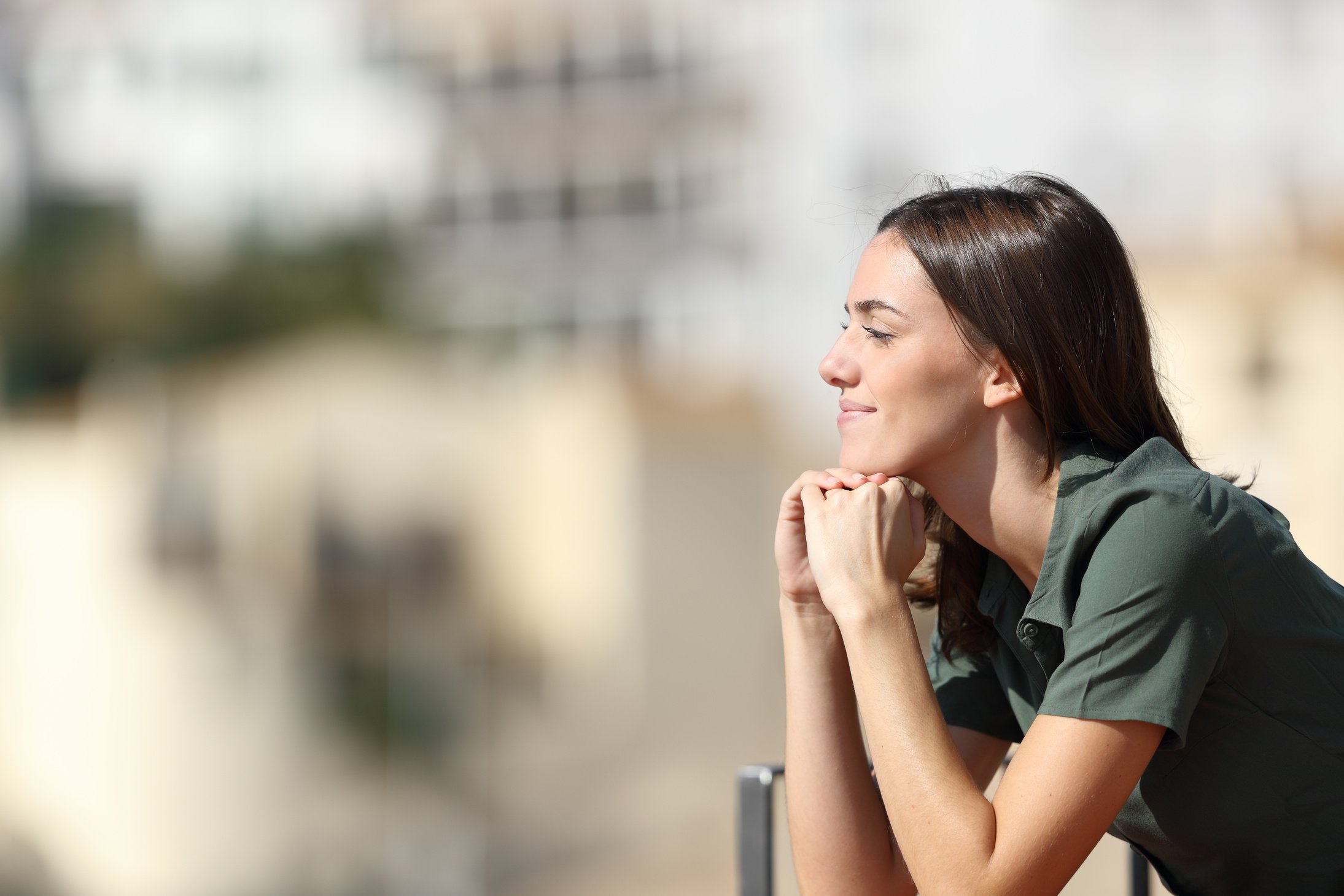 Satisfied woman contemplating from balcony in a town