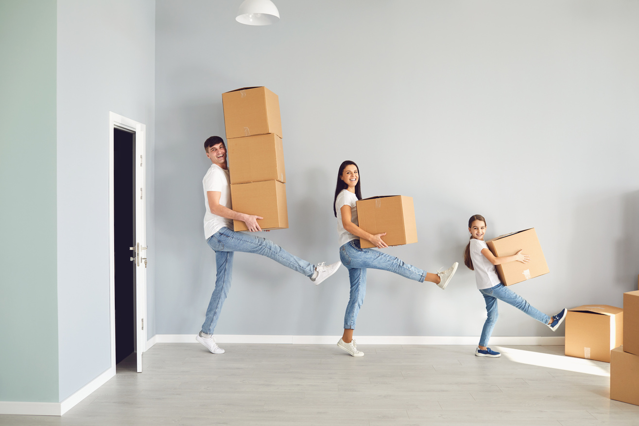 A Happy Family Is Having Fun Playing with a Box on the Floor in a New Apartment.